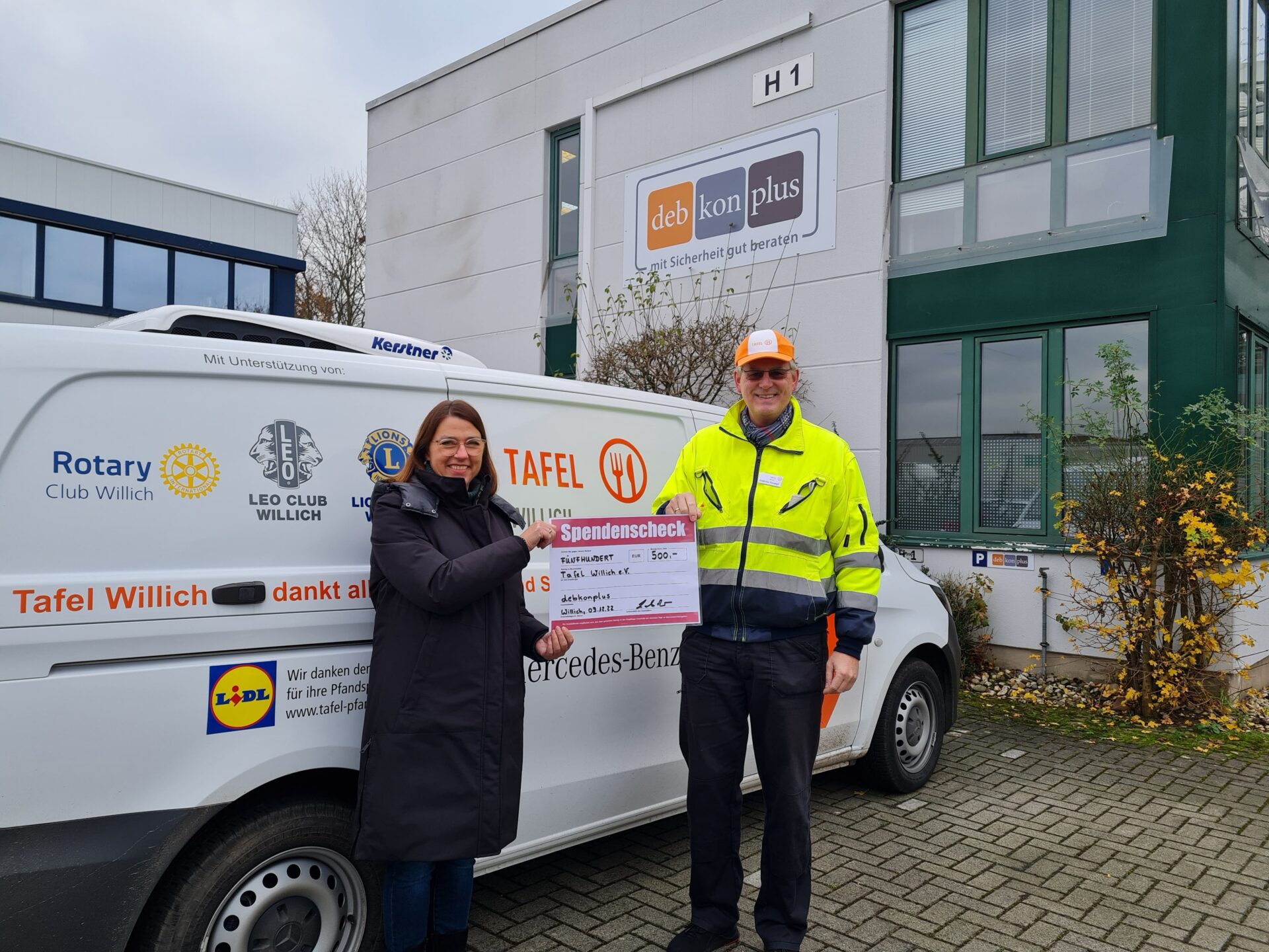 Personen mit Spendencheck vor Lieferwagen.