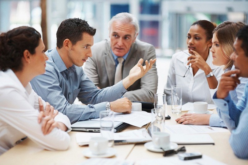 Menschen an einem hellen Tisch kommunizieren aktiv in einem Meeting.