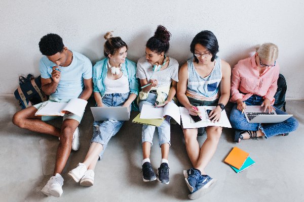 Ein Team von 5 Studenten diskutiert in einer Gruppenarbeit.