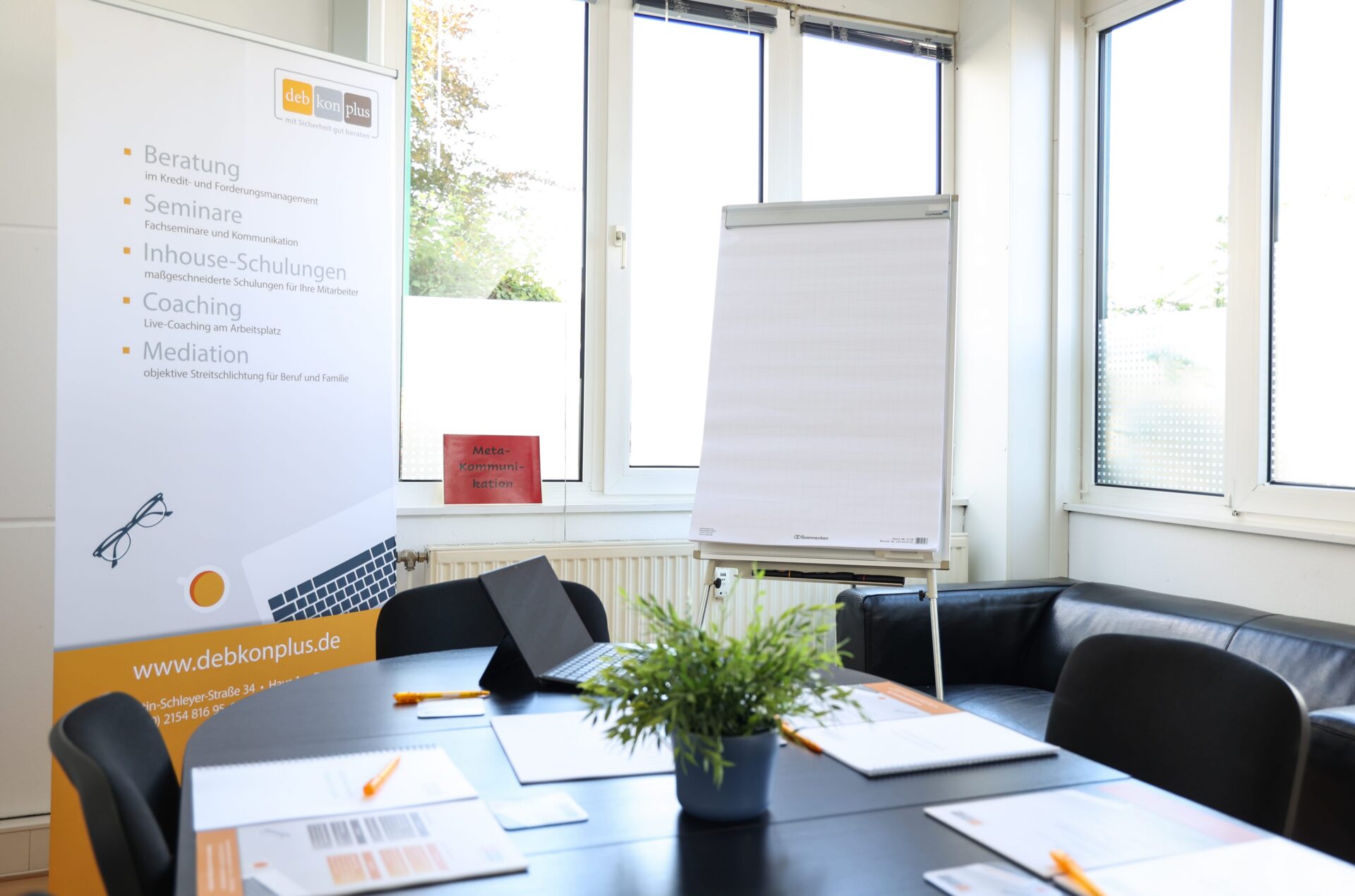 Konferenzraum mit Flipchart und Werbeplakat.