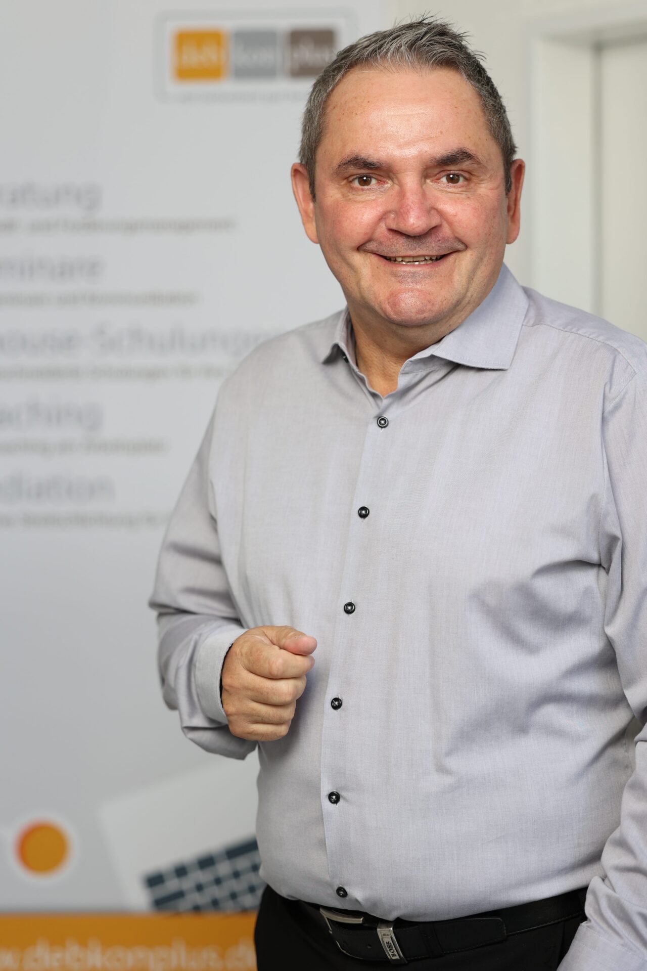 Mann in grauem Hemd vor unscharfem Hintergrund