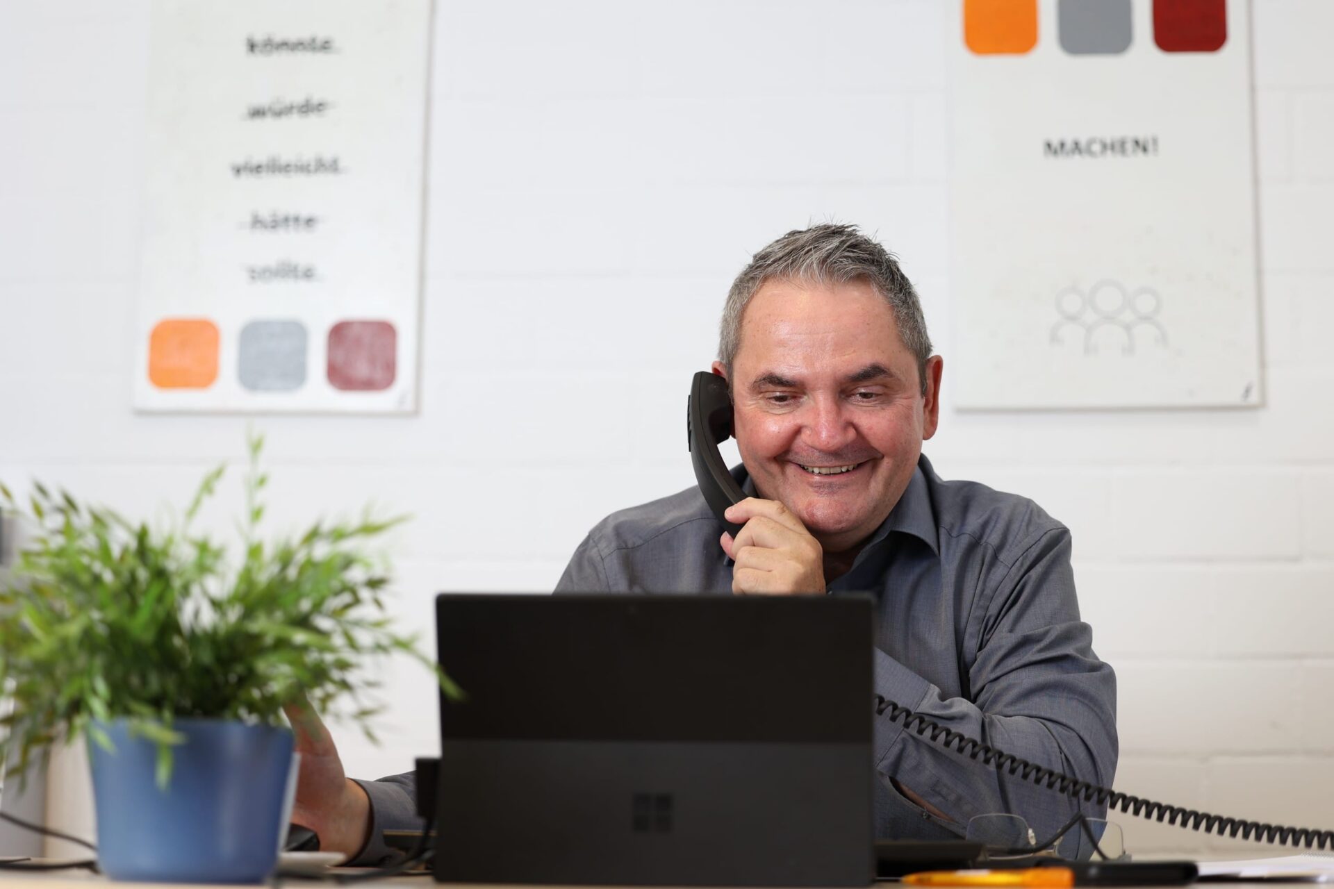 Mann telefoniert am Schreibtisch mit Laptop