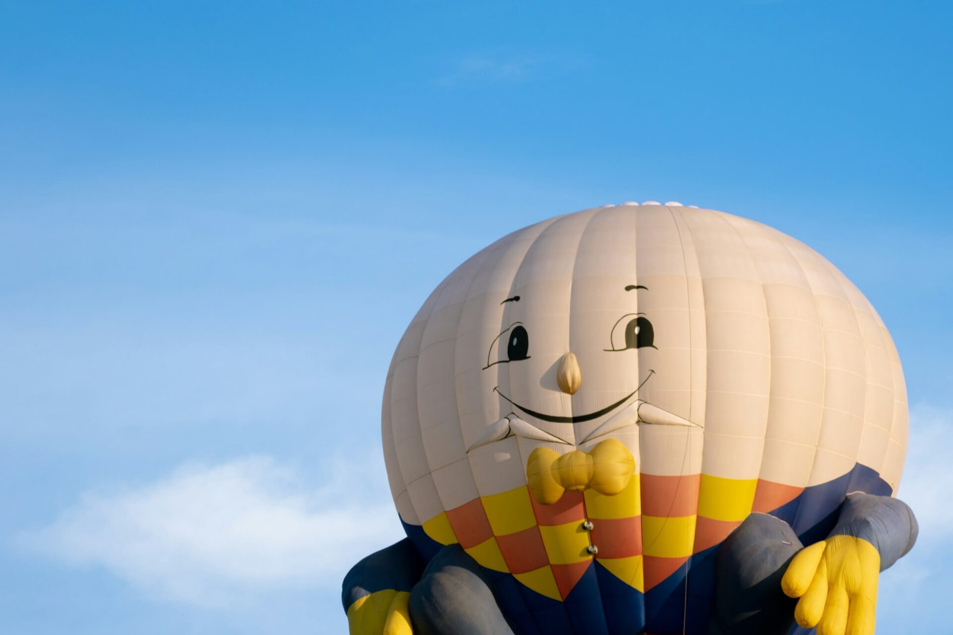 Großer Heißluftballon mit Gesicht, sonniger Himmel.