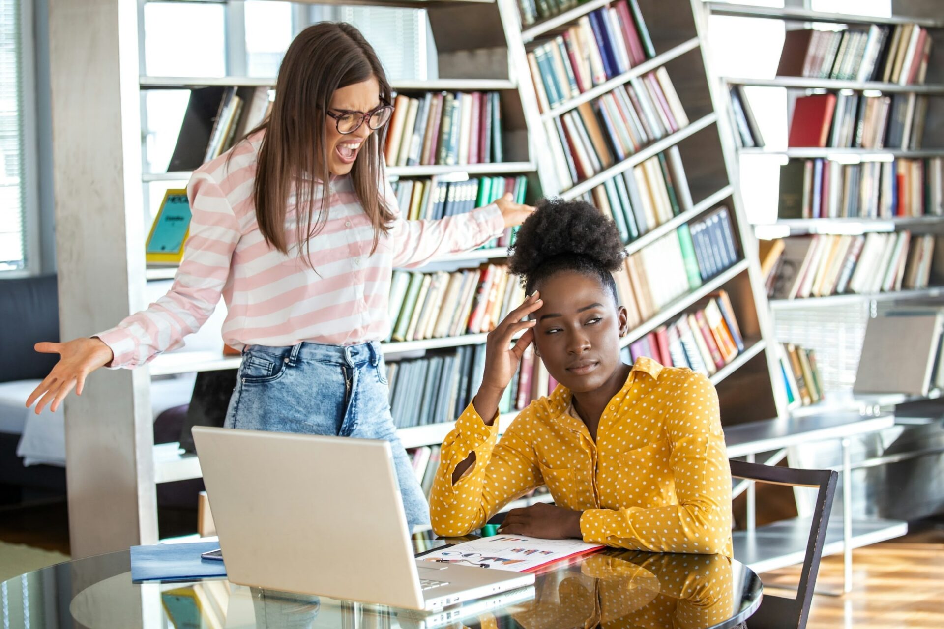 Zwei Frauen diskutieren im Büro vor Laptop.