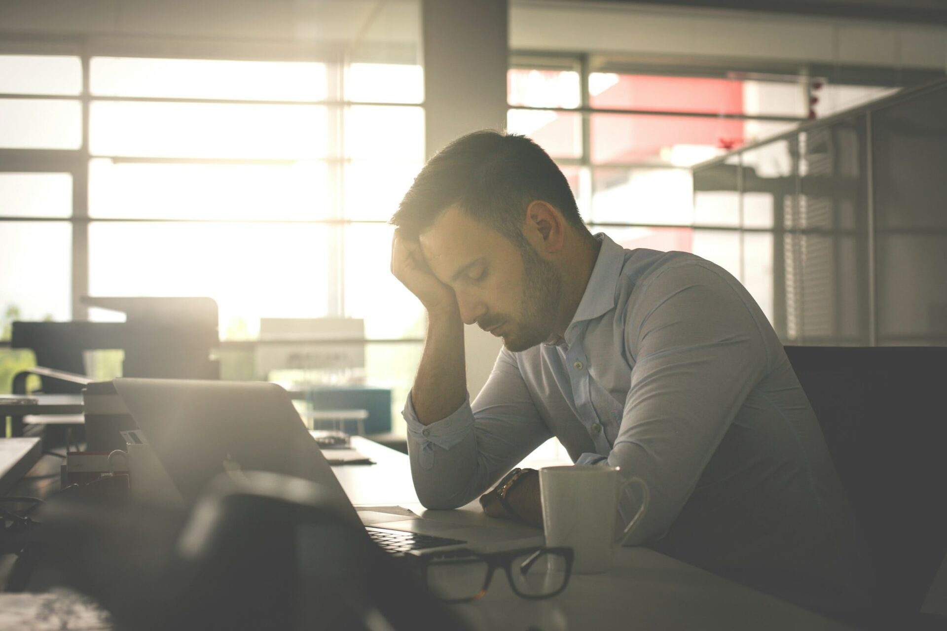 Müder Mann am Schreibtisch mit Laptop