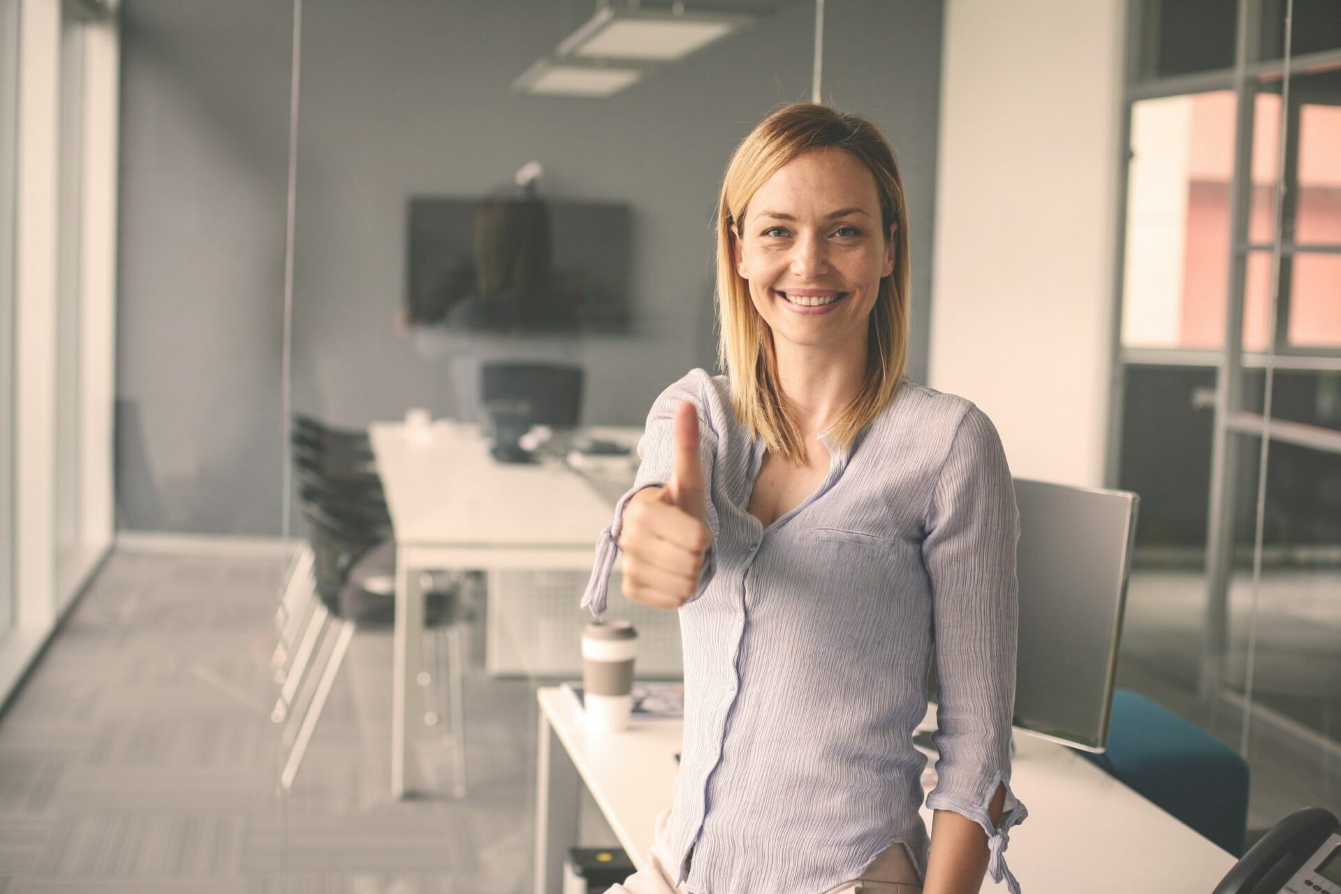 Frau zeigt Daumen hoch im Büro