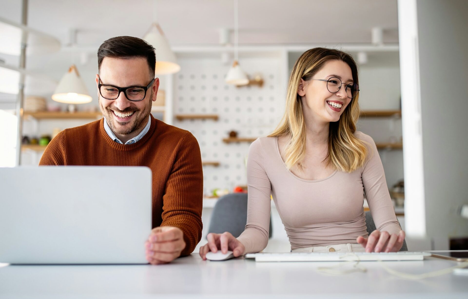 Zwei Personen arbeiten lachend am Computer.