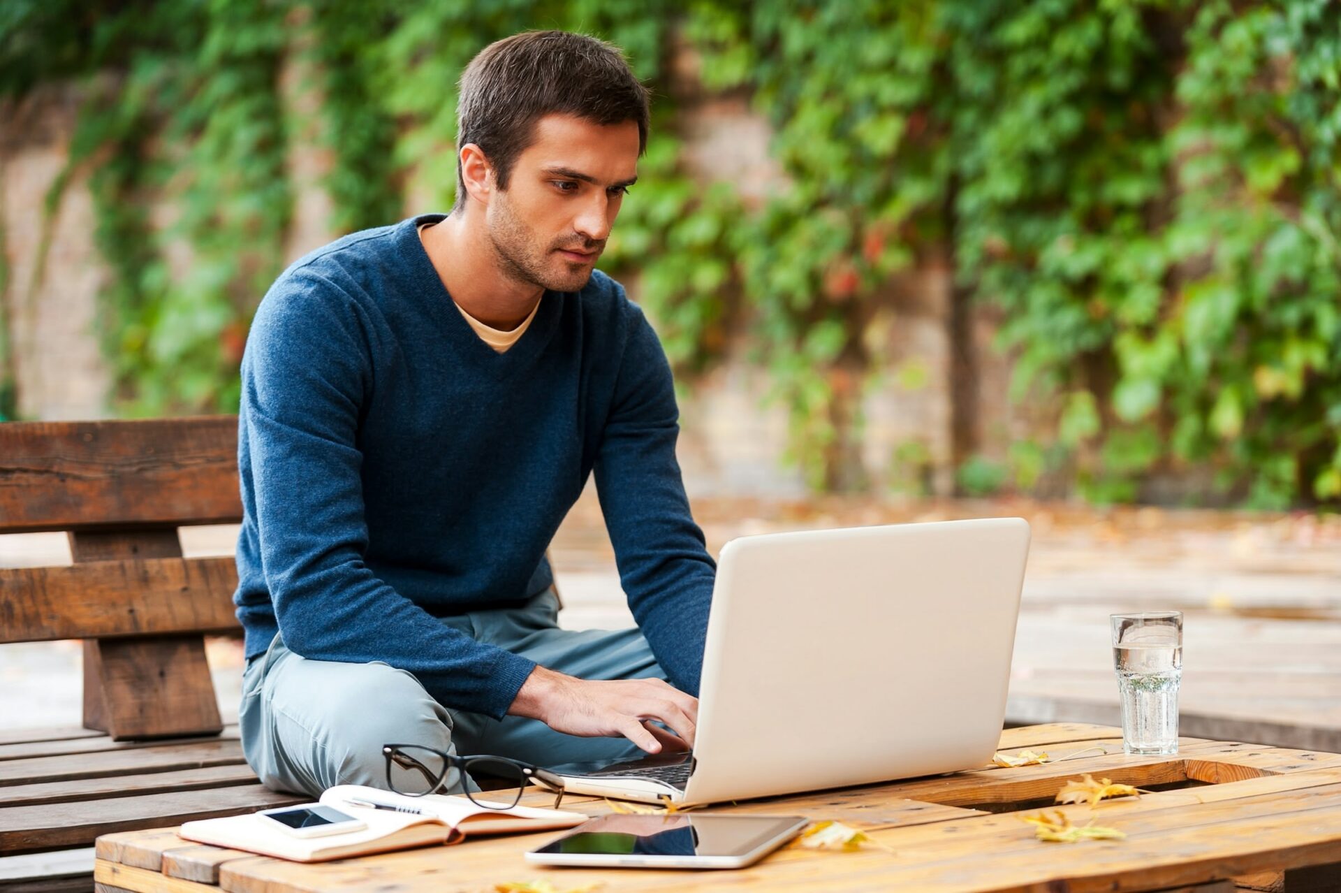 Mann arbeitet draußen mit Laptop