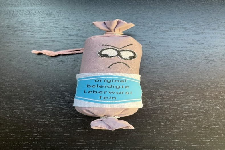 Stoffwurst mit Gesichtsausdruck und Etikett auf Tisch